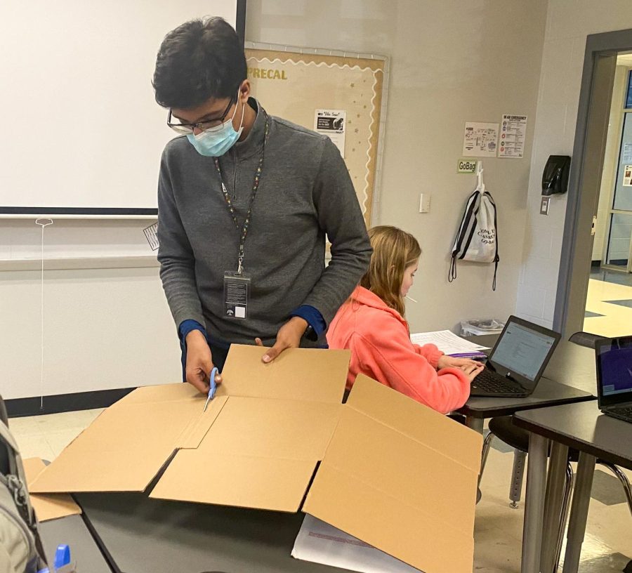 Keshav Singh cutting  cardboard to help create the rocket. The group relies on abnormal materials for construction.