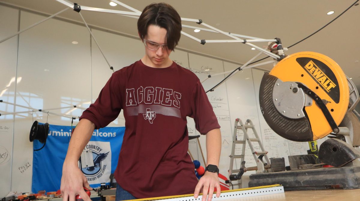 Senior Wesley Frazier measuring a piece of wood for a robot.
